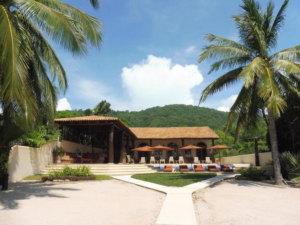 a resort with palm trees in front of it at Casa de la Costa in Troncones