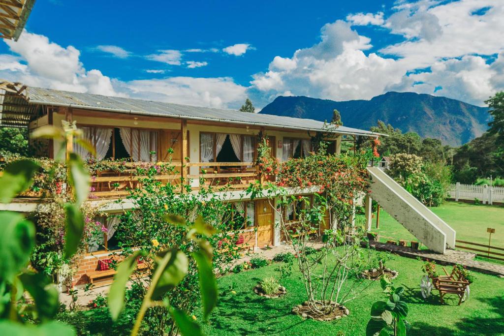 a house with a garden and mountains in the background at Posada Edelweiss in Oxapampa