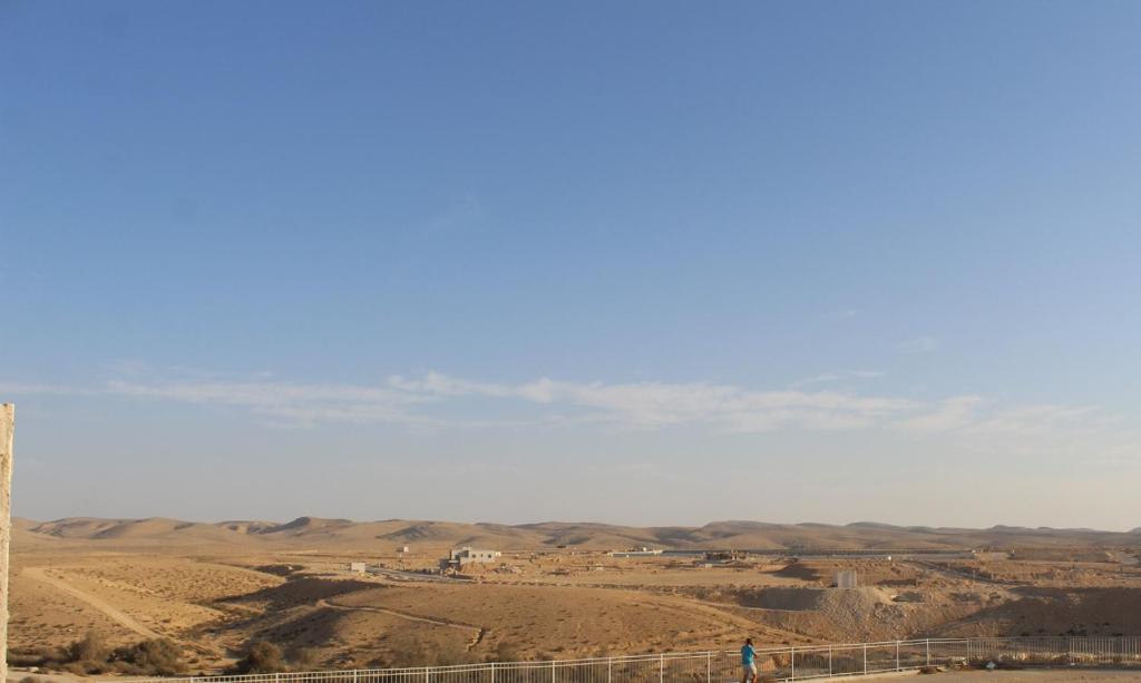 una persona caminando sobre una valla en el desierto en בית בלב מדבר little house in the desert, en Yeruham