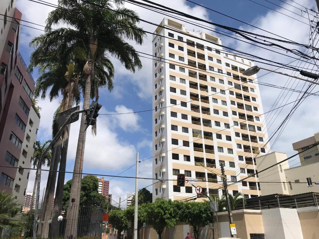 a tall white building with palm trees in front of it at Apartamento Meireles in Fortaleza