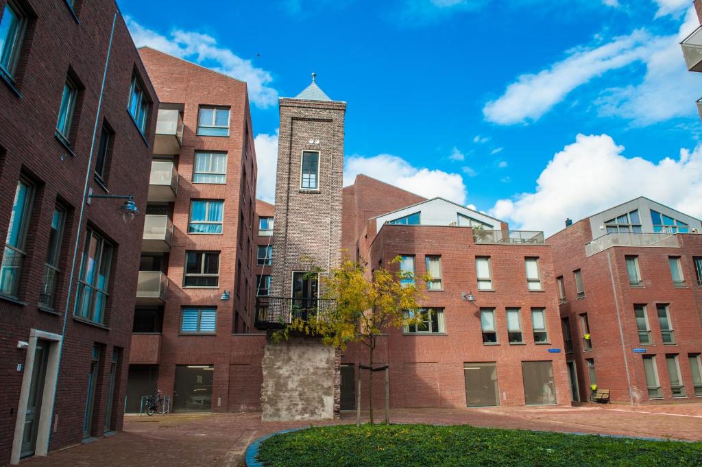 een bakstenen gebouw met een klokkentoren ervoor bij Goudse Watertoren, ’t kleinste woontorentje van Nederland in Gouda