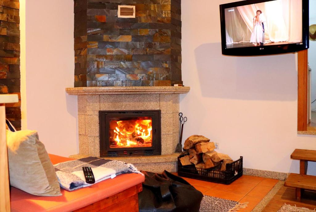 Una sala de estar con chimenea y televisión. en Casa da Quiana, en Digueifel