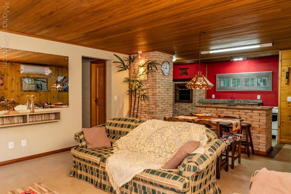 sala de estar con sofá, mesa y cocina en Chalé Bela Vista en Gramado