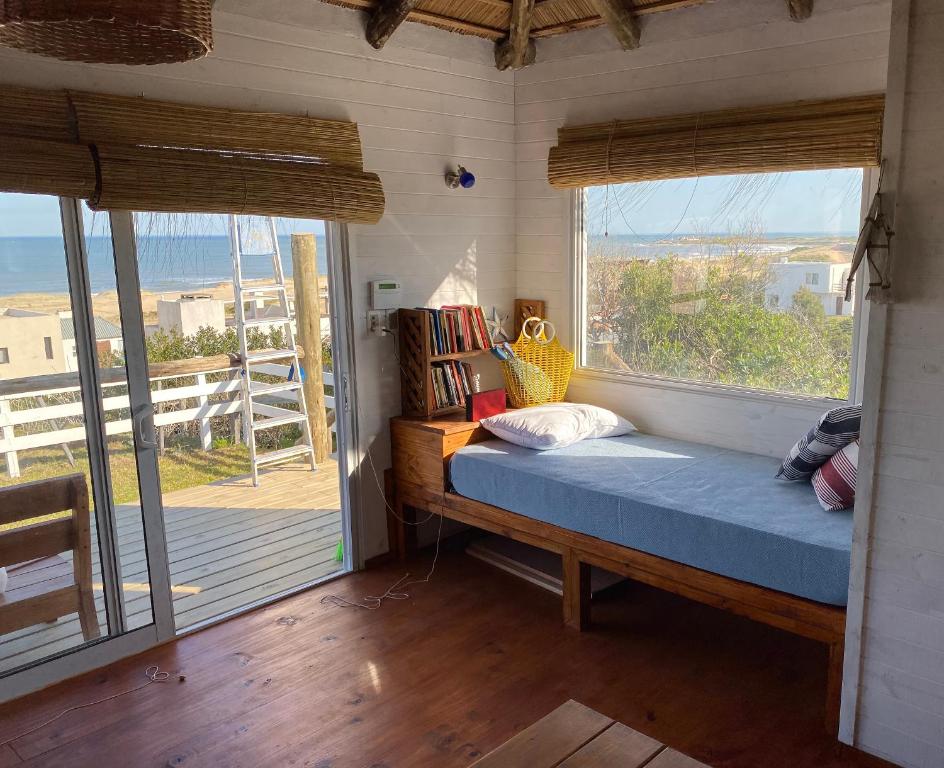 a bedroom with a bed and a large window at Cabañas Punta Papaya in Punta Del Diablo