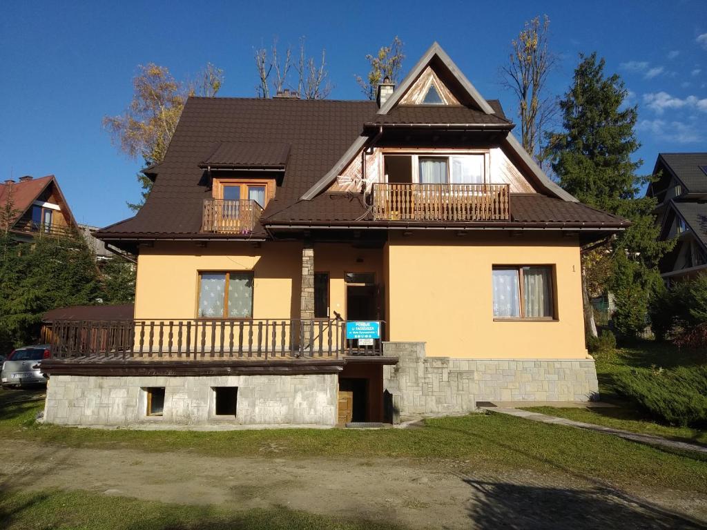 a large yellow house with a black roof at Pokoje u Tadeusza in Zakopane