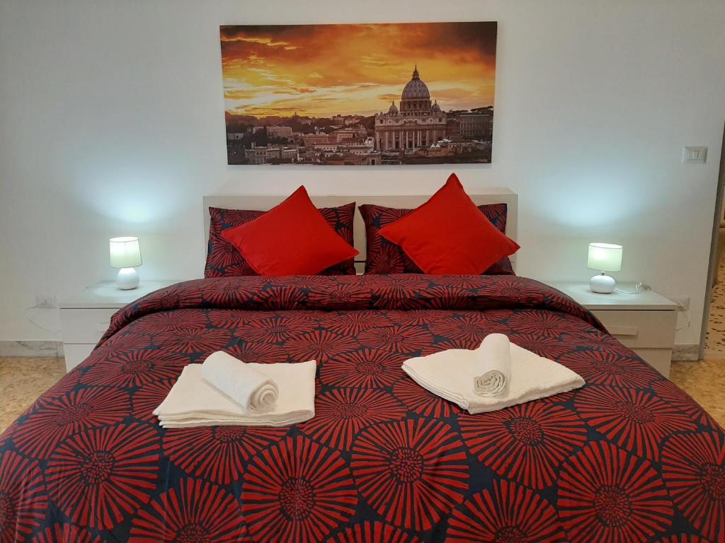centro monti tiburtini في روما: غرفة نوم بسرير ومخدات حمراء ومناشف