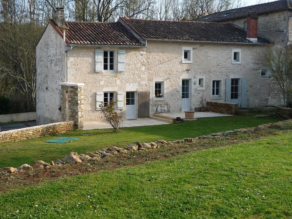 uma grande casa de pedra branca com um quintal em Le Logis de Miserè em Celles-sur-Belle