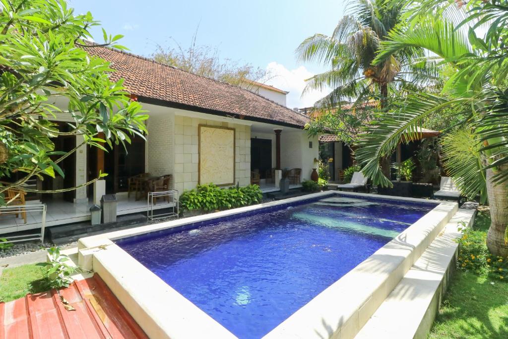 a swimming pool in front of a house at The Legian Mas Beach Inn in Kuta