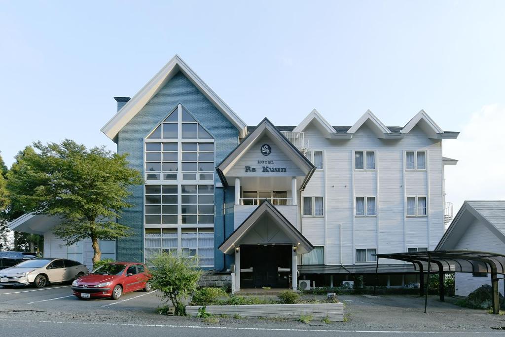een hotelgebouw met auto's geparkeerd op een parkeerplaats bij Hotel Ra Kuun in Hakone