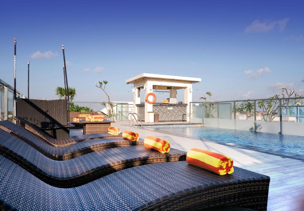 a swimming pool with yellow and orange pillows on top of a building at Zia Hotel Kuta in Kuta