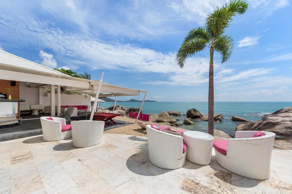 a patio with chairs and a palm tree and the ocean at Beluga Boutique Hotel in Lamai