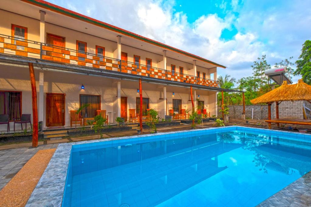 a hotel with a swimming pool in front of a building at Jeri Home Stay in Kuta Lombok