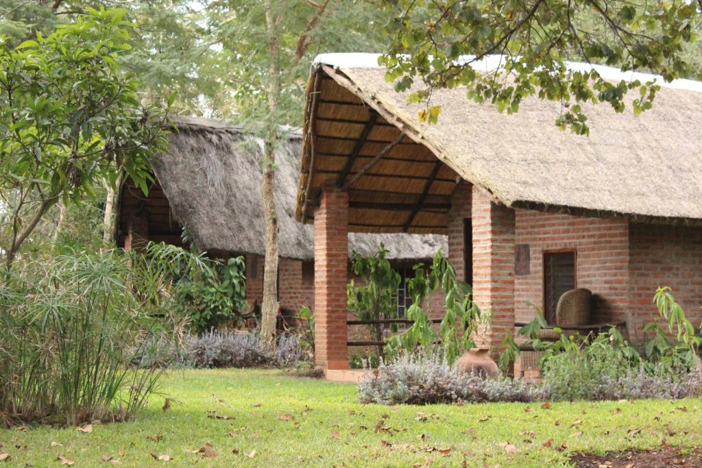 a brick house with a thatched roof in a yard at Barefoot Lodge and Safaris - Malawi in Lilongwe