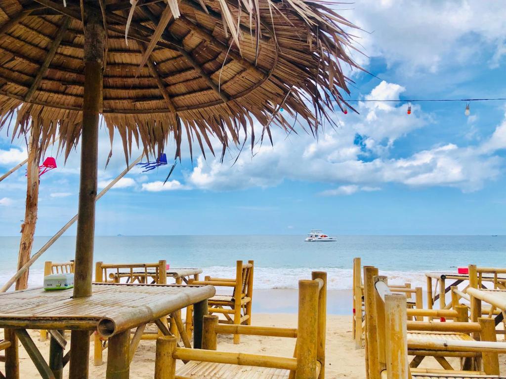 a wooden table and chairs on a beach with the ocean at Lanta Palm Beach Resort Krabi , Koh Lanta - SHA Plus in Ko Lanta