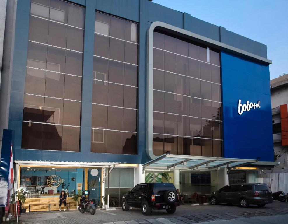 ein großes blaues Gebäude mit einem Jeep-Händler in der Unterkunft Bobotel Gatot Subroto Medan in Medan