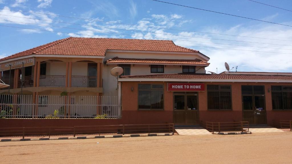 a building with a sign that reads home to home at Zawadi Hotel in Adjumani