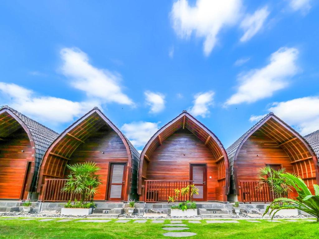 a row of wooden homes on a lawn at Sekar Arum Riverside Resort in Canggu in Tanah Lot