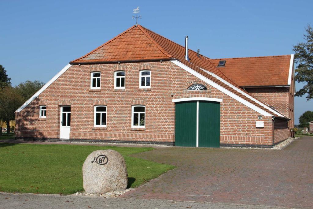 un gran edificio de ladrillo con un garaje verde en Ferienwohnung im Gulfhof, 65269, en Moormerland