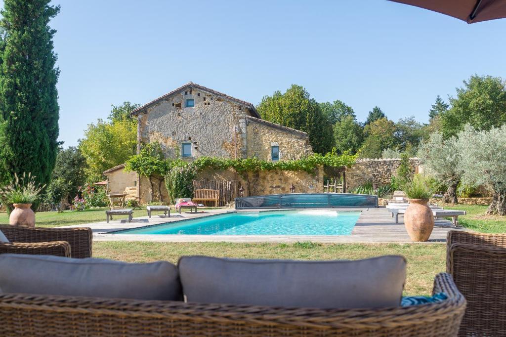 una piscina frente a un edificio con una casa en B&B, Chambres Dordogne, Clos de Saint-Maime en Vergt