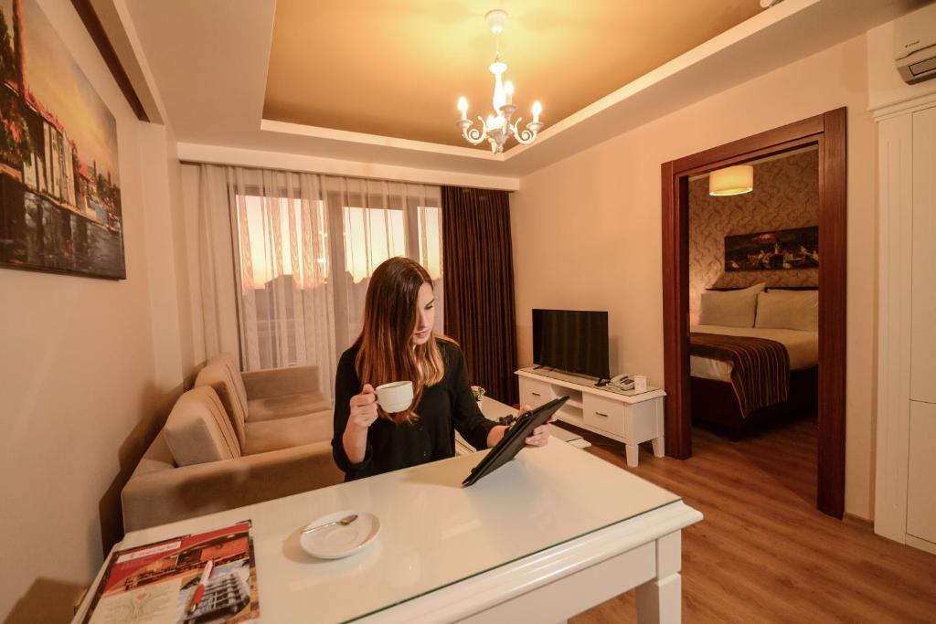 een vrouw met een kopje koffie in een hotelkamer bij Sarajevo Suit Hotel in Kocaeli