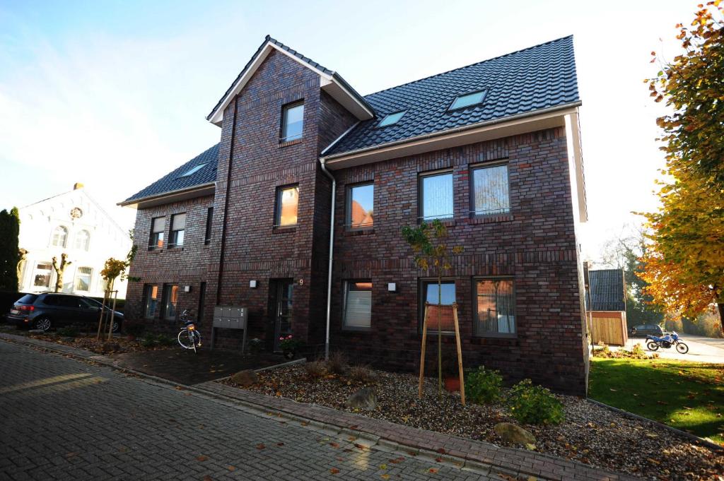 a brick house with a black roof on a street at Ferienhaus Zur Alten Maar, 65332 in Moormerland