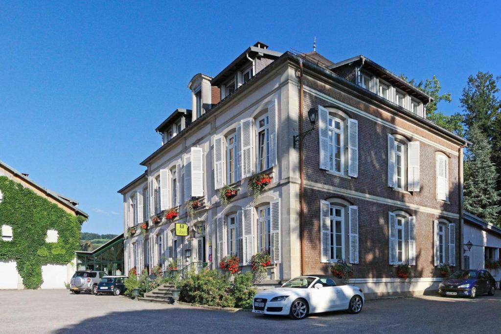 a white car parked in front of a building at Logis La Résidence in Le Val-dʼAjol