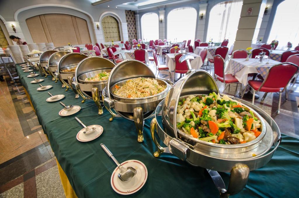 A buffet line of covered hot dishes beside a bright dining room.
