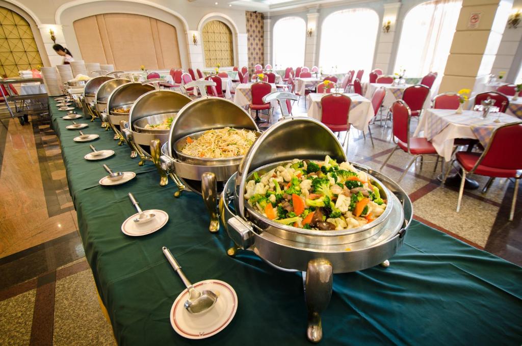 A long buffet counter of hot dishes overlooking a red-seated dining room.