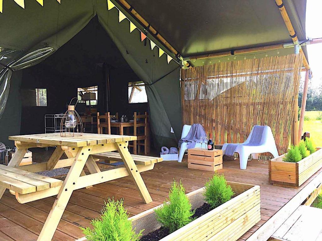 a wooden picnic table and chairs in a tent at Wingfield Escapes in Diss