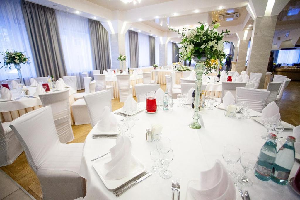 a room filled with white tables and white chairs at AZIMUT Hotel Siberia in Novosibirsk