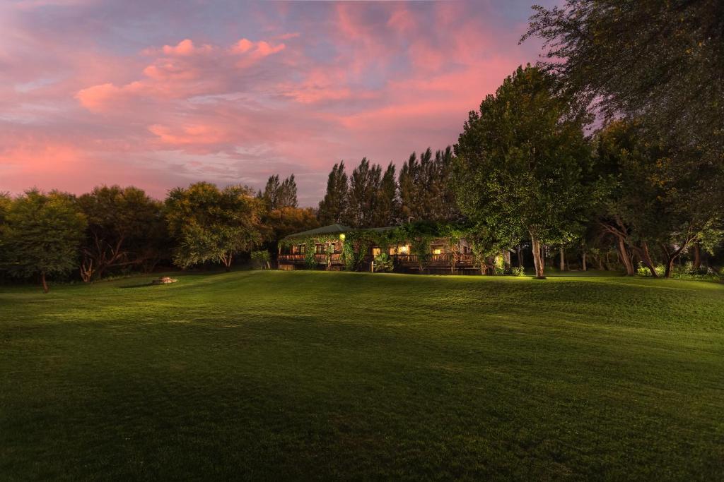 een grote tuin met een huis in het midden van een veld bij Tzamenkomst River Lodge in Colesberg
