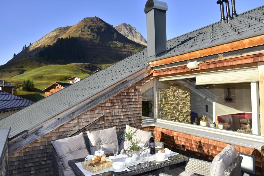 a patio with a table and chairs and a mountain at Alpenappartement Bergkönig in Warth am Arlberg