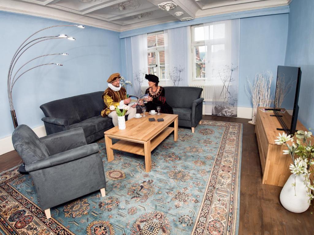 two people sitting in a living room with a table at Lutherwohnung in Schmalkalden