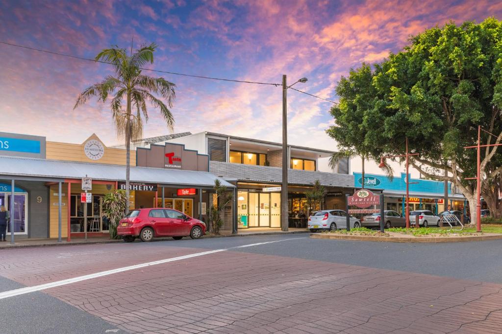 a street in a town with cars parked in front of a building at 13 First Avenue Sawtell in Sawtell