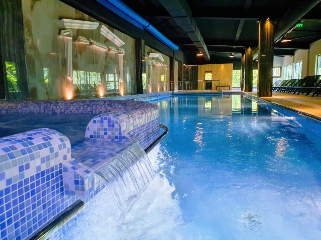 a large swimming pool with chairs in a building at Hotel Posada Vidraru in Căpăţîneni-Ungureni