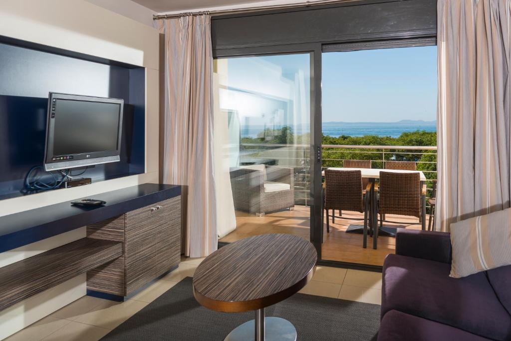 a living room with a television and a balcony at Apartaments Terraza - Salatà Mar in Roses