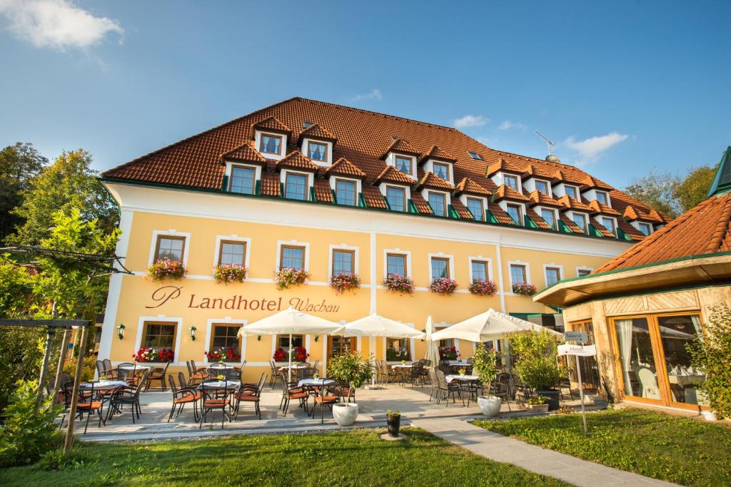 een groot gebouw met tafels en stoelen ervoor bij Landhotel Wachau in Emmersdorf an der Donau