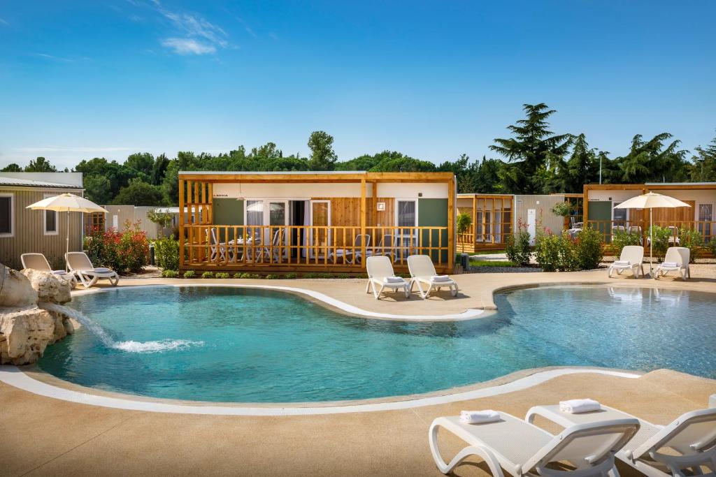 a swimming pool with chairs and a house at Maistra Camping Polari Mobile homes in Rovinj