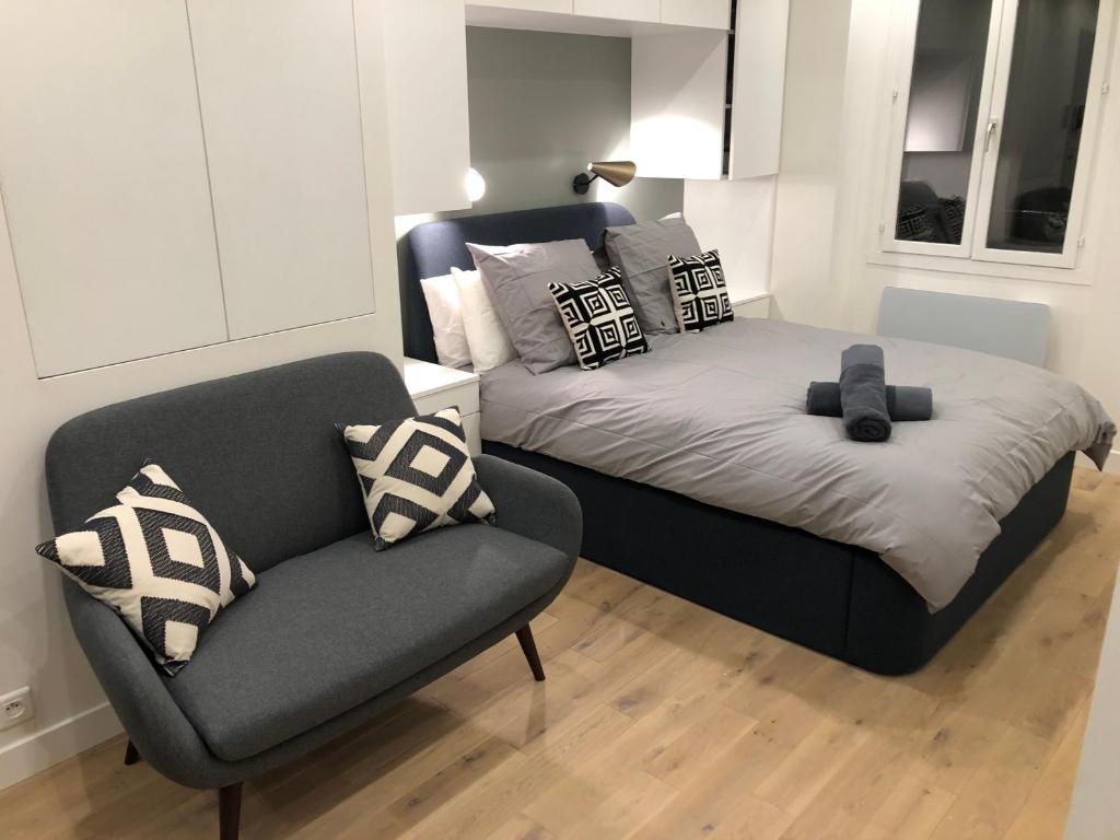 un letto e una sedia in una stanza di Studio design proche Champs-Elysées a Parigi