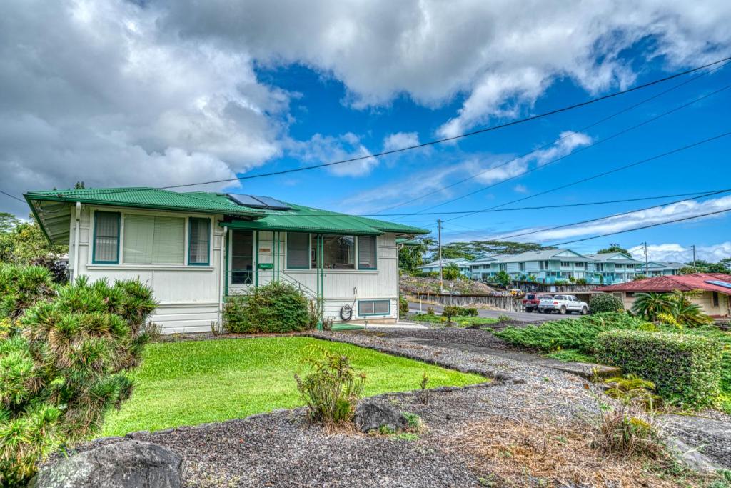 a house with a green roof and a yard at Hale Ulu Kealoha in Hilo