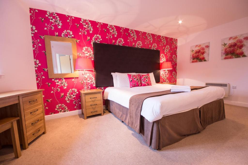 a bedroom with two beds and a pink wall at Hartington Cottage - Darwin Lake Holiday Village in Matlock