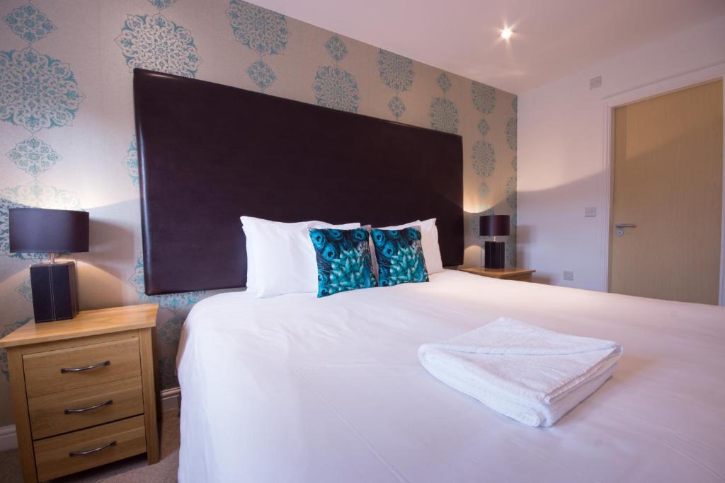 a bedroom with a large white bed with a large headboard at Hartington Cottage - Darwin Lake Holiday Village in Matlock