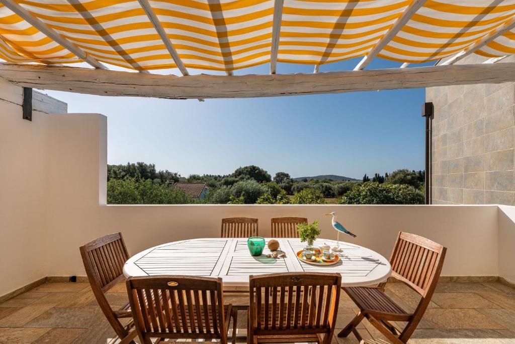 una sala da pranzo con tavolo, sedie e una grande finestra di Villa Fico 2 a Domus de Maria