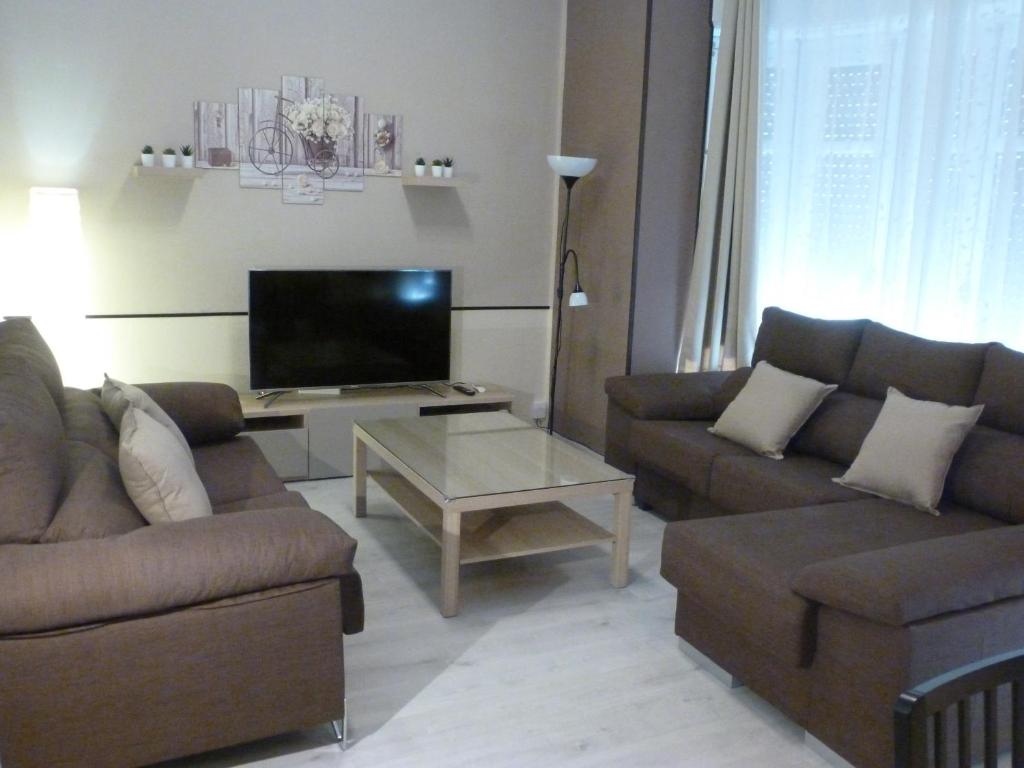 ein Wohnzimmer mit 2 Sofas und einem Flachbild-TV in der Unterkunft Apartamentos Turia in Valencia