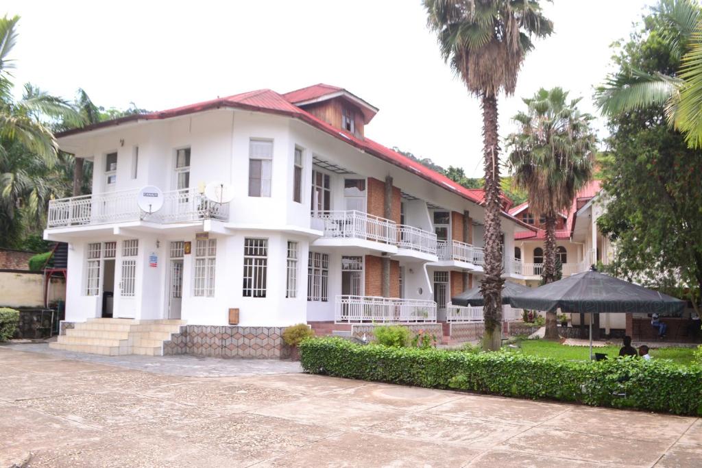 a white building with palm trees in front of it at Musanto Hotel in Gisenyi