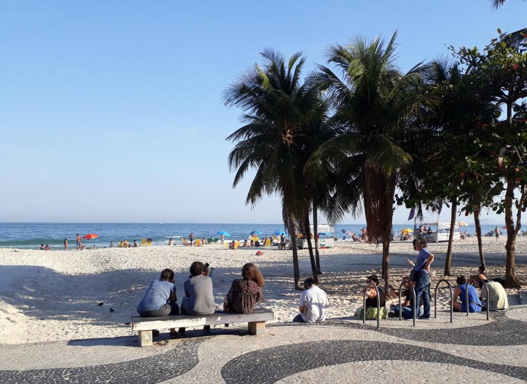 um grupo de pessoas sentadas em bancos na praia em Casa Babilonia no Rio de Janeiro