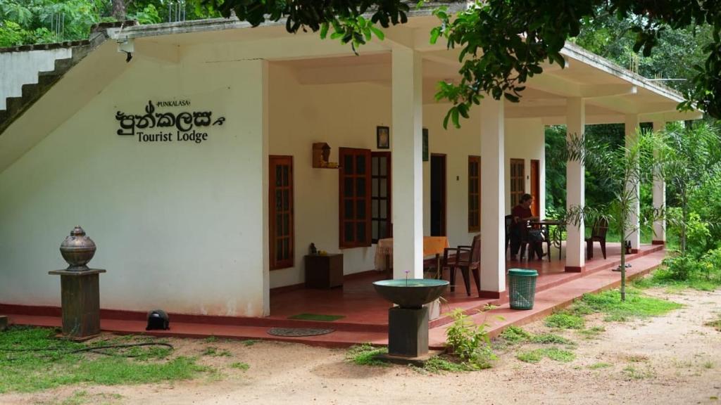 a white house with a table and chairs at Punkalasa tourist lodge in Anuradhapura