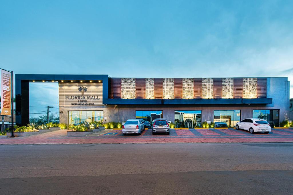 two cars parked in a parking lot in front of a building at Florida Mall & Suites in Limeira