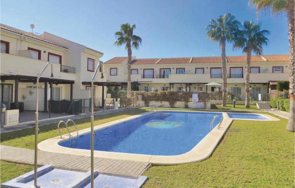 a swimming pool in front of a building with palm trees at Nice Home In Ciudad Quesada With Kitchenette in Ciudad Quesada