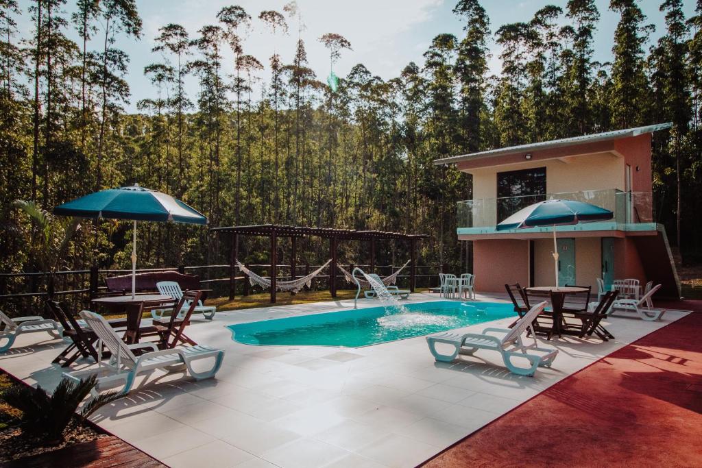 a patio with a pool and chairs and a table and umbrella at RECANTO DA SERRA in Mauá da Serra